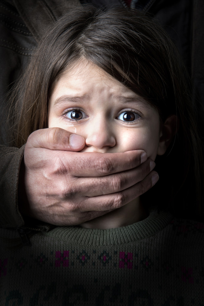 Scared young girl with an adult man's hand covering her mouth - domestic violence