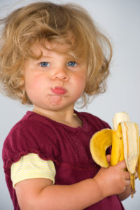 blond, pouty-looking girl eating banana -