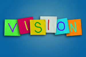 The word VISION written in colorful sticky notes on a blue background for classes in a training venue