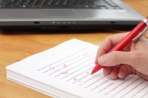 hand with red pen editing manuscripts for Write by the Rails publications