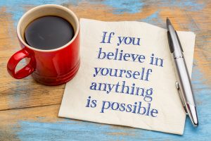 If you believe in yourself anything is possible - handwriting on a napkin with a red cup of espresso coffee Overcoming Imposter Syndrome