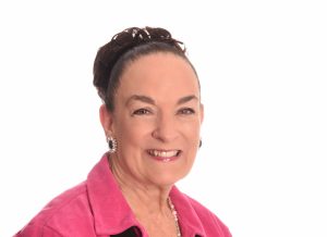 Headshot of Nancy Wyatt with her brown hair in a bun, wearing a pink and black suit with black earrings, Owner, My Persuasive Presentations, LLC